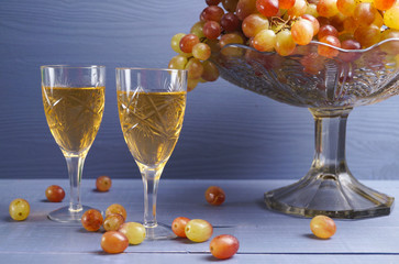 glass of young wine with grapes blue background - vintage