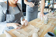 © pressmaster - Young woman sitting by table and making clay workpieces before creating earthenware