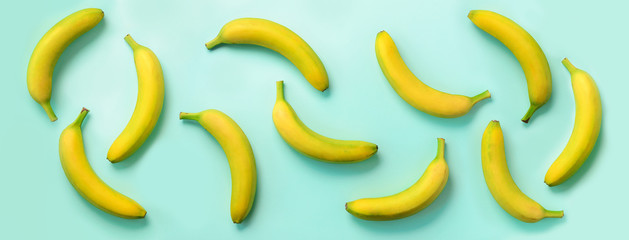 Wall Mural - chaotic colorful fruit pattern. bananas over blue background. banner. top view. pop art design, crea