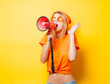 © Masson - Young style girl in orange clothes with pink megaphone on yellow background. Symbolizes female resistance. Clothes in 1980s style