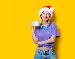 Wall Mural - Young style girl in purple clothes and Christmas hat and cup on yellow background.  Clothes in 1980s style