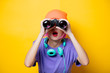 © Masson - Young style girl in purple clothes with binoculars on yellow background.  Clothes in 1980s style
