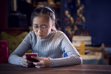 face of asian teenager reading message on smart phone in home living room