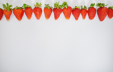 strawberry fruits in a row on white wood table background