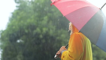 happy young attractive girl holding colorful umbrella while walking outdoors in rainy day cute smile