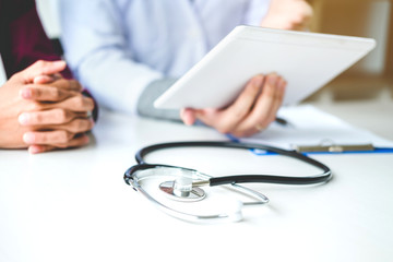 Wall Mural - Doctor consulting with patient presenting results on digital tablet tablet  sitting at table