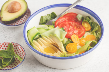 Canvas Print - Green zucchini noodles salad with tomatoes, avocado and basil. Healthy vegan zucchini pasta.