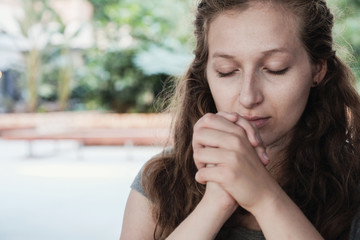 Young woman praying with eyes closed