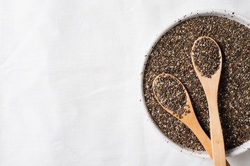 Chia seeds in bowl with two wooden spoon close up