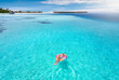Attraktive Frau treibt auf aufblasbaren Lolli über das türkise Wasser der Malediven und genießt ihren Urlaub