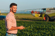 © Zoran Zeremski - Young farmer in filed holding tablet in his hands and examining soybean corp.