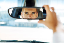In the car. Close up of a rearview mirror with a smart skillful driver looking into it