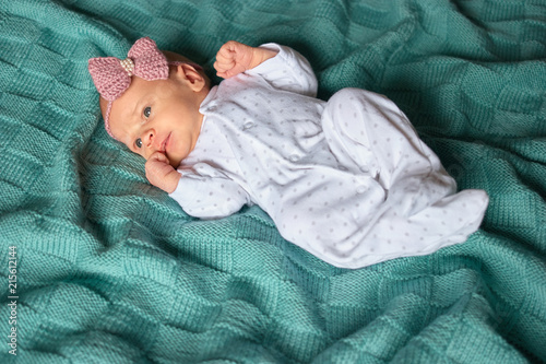 Fotografía Newborn baby girl with bow in white footed pajamas