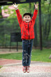 little boy joyfully jumping up against the park background