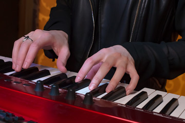 Girl musician plays the MIDI synthesizer keyboard, focus on hands