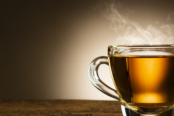 Wall Mural - closeup of steamed glass cup of tea on wooden table