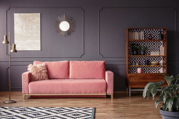 Wall Mural - A marble beige painting and a sunburst golden mirror on a gray wall with molding in a stylish living room interior with a velvet, powder pink sofa and retro furniture