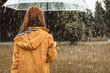 Autumn solitude. Woman standing with back turned and holding umbrella outdoors. She is strolling on her own enjoying wet weather. Copy space in right side