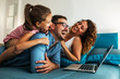 © BalanceFormCreative - Happy family lying on bed and watching something on laptop. Laughing and having fun.