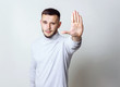 Portrait of young bristle man raising hand up to say no stop right there or talk to hand, on gray background. Emotion facial expression feelings, signs symbols, body language. Copy space