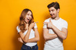 © Drobot Dean - Image of happy young people man and woman in basic clothing laughing and pointing fingers at each other, isolated over yellow background