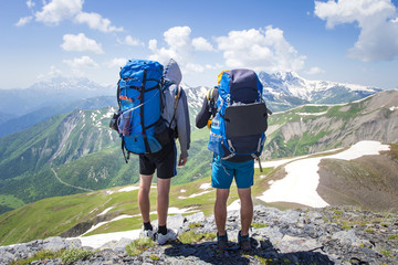 Wall Mural - two hikers in mountains with backpacks on sunny summer day. mountain trek in svaneti, georgia. touri