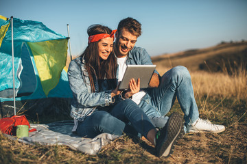 Wall Mural - Happy young couple using digital tablet on sunny day in nature