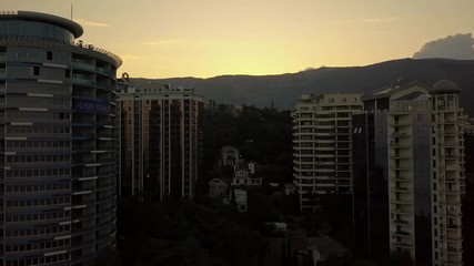 Wall Mural - silhouette of tall skyscraper living buildings apartments on a sunset time in near the mountains and clouds above