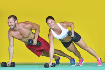 Wall Mural - Beautiful fitness young sporty couple doing push ups together indoors.