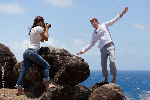 Fotografie, Obraz Young Man Clowns Around While Young Woman Takes His Photo on a Cliff