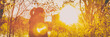 © Maridav - Autumn woman in beautiful autumn yellow sun flare nature with falling leaves over forest background. Panoramic banner header portrait.