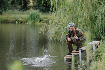 Wall Mural - Fishing in river.A fisherman with a fishing rod on the river bank. Man fisherman catches a fish pike.Fishing, spinning reel, fish, Breg rivers. - The concept of a rural getaway. Article about fishing.