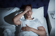 © New Africa - Handsome young man suffering from headache while lying in bed at night