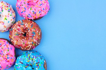 Poster - Side border of assorted donuts with frosting and sprinkles against a pastel blue background