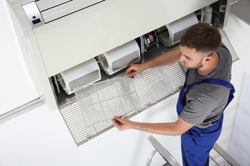 Canvas Print - Young male technician cleaning air conditioner indoors