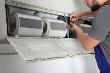 Poster - Young male technician repairing air conditioner indoors