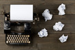 Vintage typewriter top down flatlay shot from above with empty, blank sheet of paper and crumbled paper balls on wood table