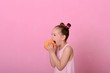 © Alla - Caucasian beautiful little girl eating grapefruit on a pink background.