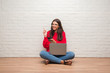 © Krakenimages.com - Young brunette woman sitting on the floor using laptop and smartphone surprised with an idea or question pointing finger with happy face, number one
