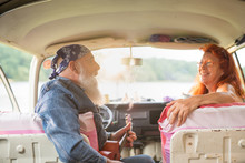 An Old Hipster Couple Sitting In A Van, The Man Playing Ukulele 