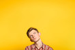 pensive thoughtful contemplative brooding man looking up. portrait of a young guy on yellow background popping up or peeking out from the bottom. copyspace for advertisement.