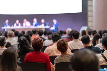 Rear view of Audience in the conference hall or seminar meeting which have Speakers are Brainstorming and talking on the stage, business and education about investment concept