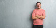 © Krakenimages.com - Young caucasian man over grey grunge wall skeptic and nervous, disapproving expression on face with crossed arms. Negative person.