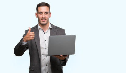 Poster - Handsome young man using computer laptop happy with big smile doing ok sign, thumb up with fingers, excellent sign