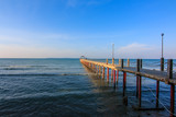 Fototapeta Morze - Concrete jetty into the sea on blue sky background