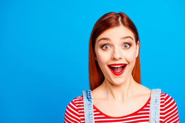 Portrait of nice fool girlish red straight-haired happy young girl with opened mouth, isolated over blue background, copy space