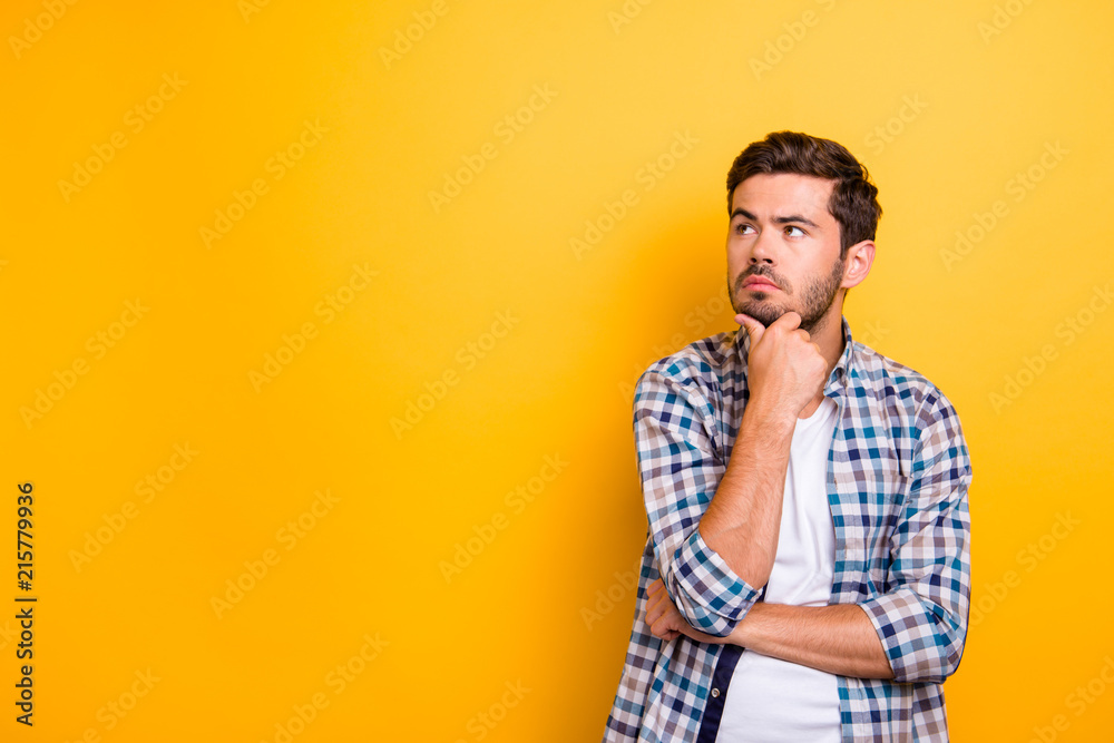 Close up portrait of thoughtful man who looks away touching his chin and weighs the pluses and minuses of the offer isolated on bright yellow background with copy space for text - obrazy, fototapety, plakaty 