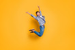 © deagreez - Full-body portrait of flying and cheerful man in sneakers, denim outfit, jumping with raised arms isolated on shine yellow background