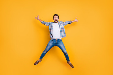 Full-legh portrait of of crazy and excited handsome man jumping up like a star isolated on shine yellow background