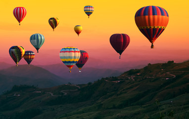 Hot Air balloons flying over road in forest landscape sunset background.